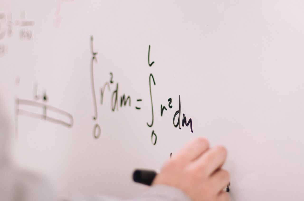Home Person writing math equations on a whiteboard, focusing on integrals and formulas.